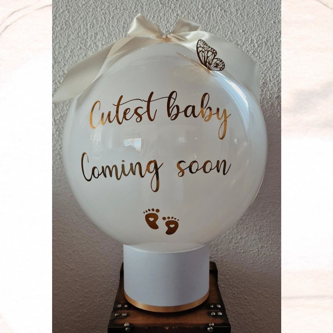 Ballon «Cutest baby coming soon» auf weisser Box zur Schwangerschaftsverkündung