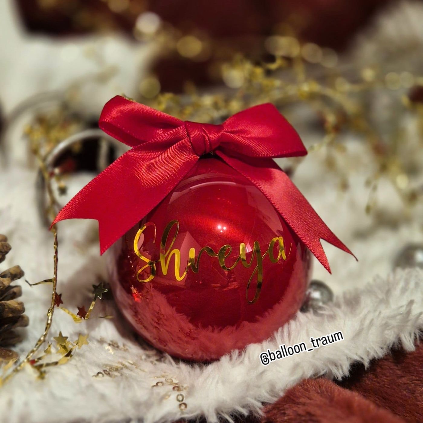 Rote Weihnachtskugel mit goldenem Namen und roter Schleife