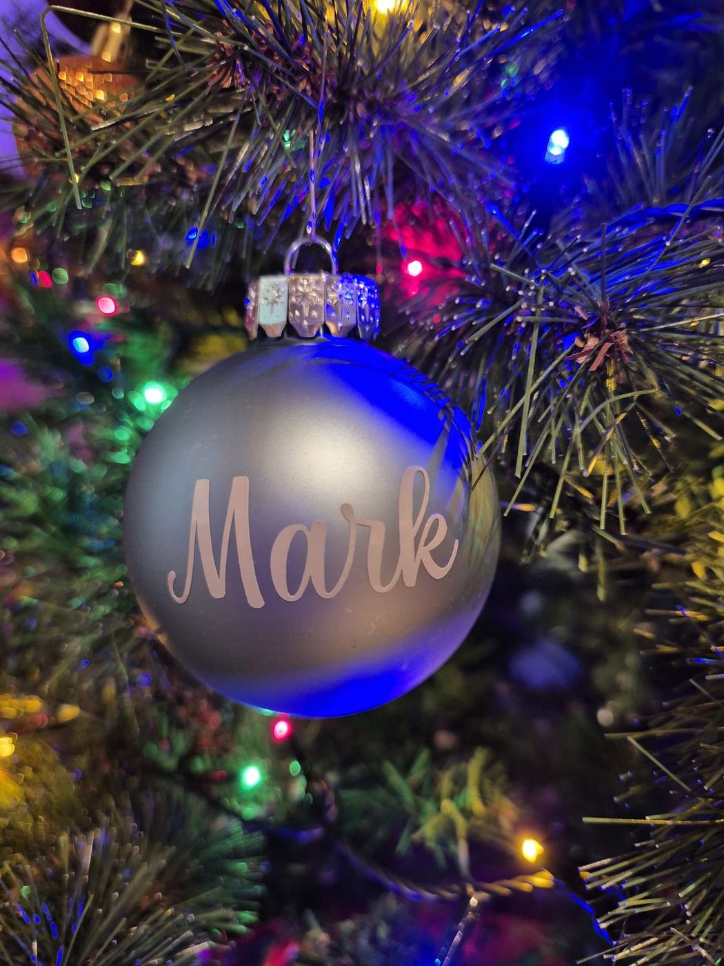 Silbern-blaue Weihnachtskugel mit Namen am Weihnachtsbaum